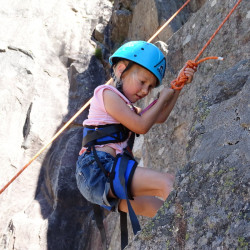 Petite fille en initiation à l'escalade sur le rocher école